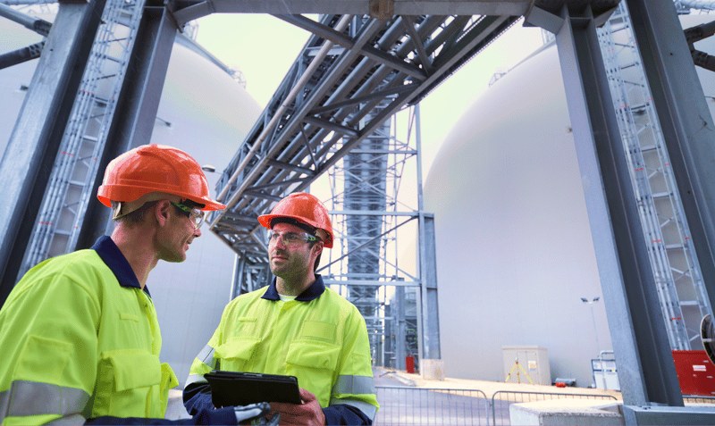 engineers in hard hats discussing results on tablet